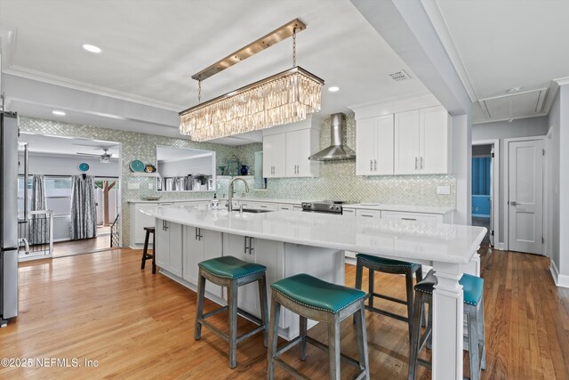 536 14th Ave N, Jacksonville Beach, FL 32250 - kitchen featuring wall chimney exhaust hood, a sink, light countertops, white cabinets, and crown molding