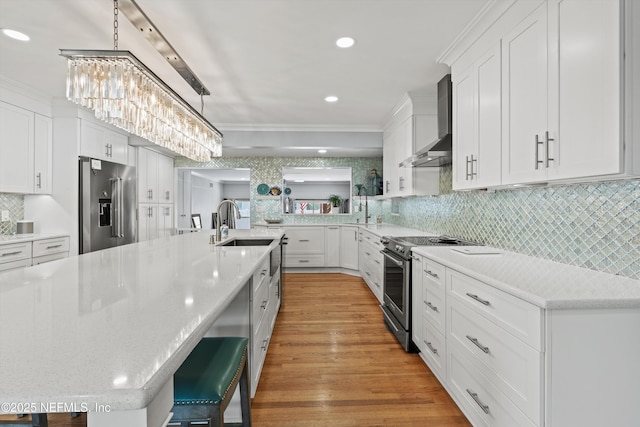 536 14th Ave N, Jacksonville Beach, FL 32250 - kitchen featuring wall chimney exhaust hood, appliances with stainless steel finishes, white cabinetry, a breakfast bar, and backsplash
