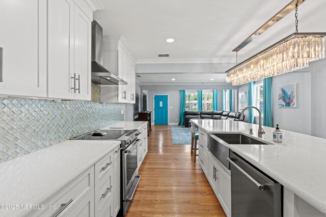 536 14th Ave N, Jacksonville Beach, FL 32250 - kitchen with wall chimney exhaust hood, appliances with stainless steel finishes, a sink, light countertops, and crown molding