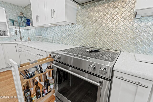 536 14th Ave N, Jacksonville Beach, FL 32250 - kitchen featuring stainless steel range with electric stovetop, tasteful backsplash, white cabinets, and light countertops