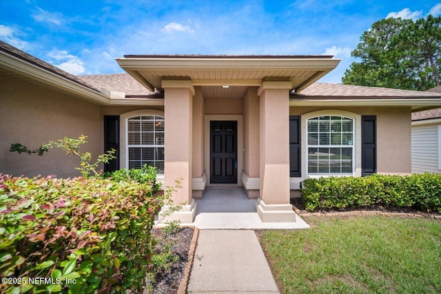 86045 Harrahs Pl, Yulee, FL 32097 - entrance to property featuring stucco siding, roof with shingles, and a yard