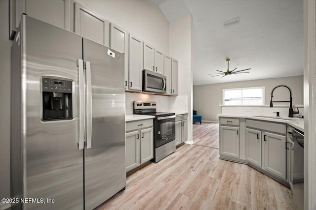 86045 Harrahs Pl, Yulee, FL 32097 - kitchen with stainless steel appliances, a sink, gray cabinets, light wood-style floors, and light countertops
