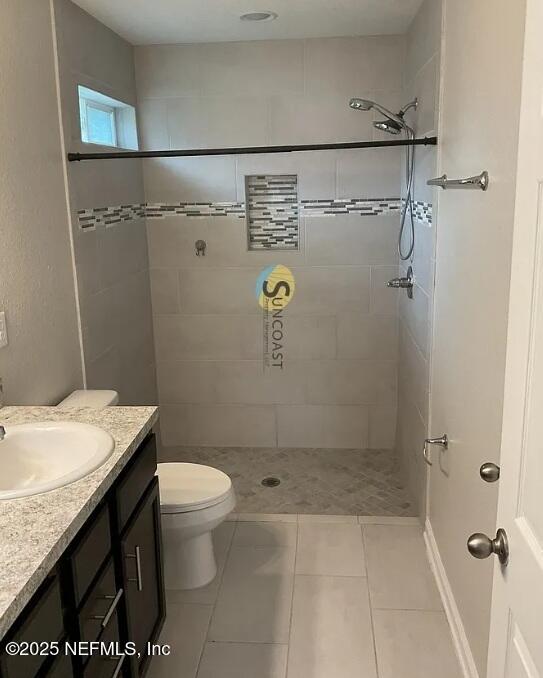 7323 Richardson Rd, Jacksonville, FL 32209 - full bathroom featuring vanity, tiled shower, toilet, and tile patterned flooring