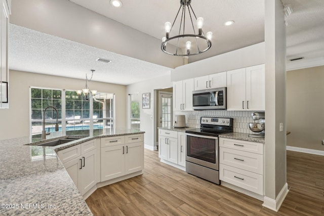 2478 Country Club Blvd, Orange Park, FL 32073 - kitchen with appliances with stainless steel finishes, a chandelier, a sink, white cabinets, and a textured ceiling