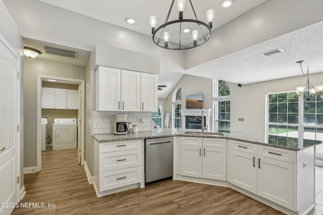 2478 Country Club Blvd, Orange Park, FL 32073 - kitchen with a chandelier, stainless steel dishwasher, washer and clothes dryer, a peninsula, and white cabinets