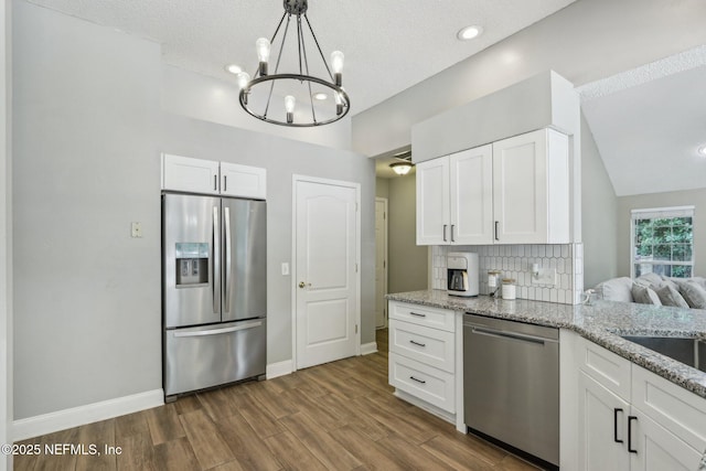 2478 Country Club Blvd, Orange Park, FL 32073 - kitchen with appliances with stainless steel finishes, a chandelier, light stone countertops, white cabinets, and dark wood-type flooring