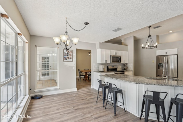 2478 Country Club Blvd, Orange Park, FL 32073 - kitchen featuring a chandelier, appliances with stainless steel finishes, a kitchen breakfast bar, white cabinetry, and light stone countertops