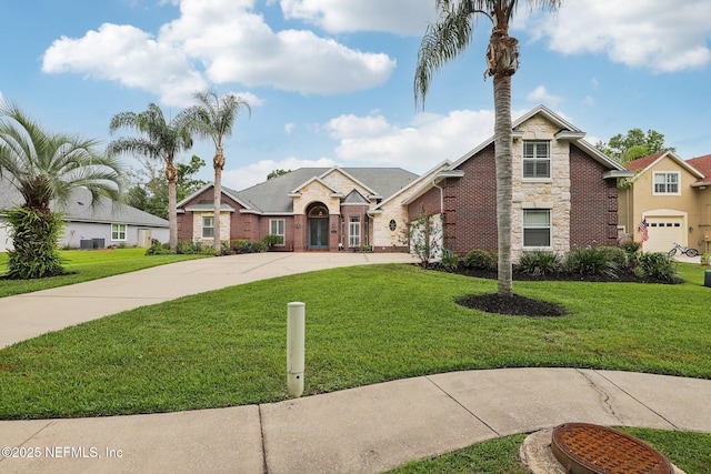 182 Malley Cove Ln, Fleming Island, FL 32003 - traditional home with curved driveway, stone siding, a front lawn, a garage, and brick siding