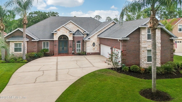182 Malley Cove Ln, Fleming Island, FL 32003 - traditional-style home featuring concrete driveway, stone siding, a front lawn, brick siding, and an attached garage