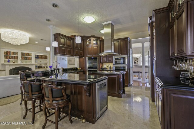 8135 Wekiva Way, Jacksonville, FL 32256 - kitchen with dark countertops, island range hood, decorative columns, dark brown cabinetry, and a textured ceiling