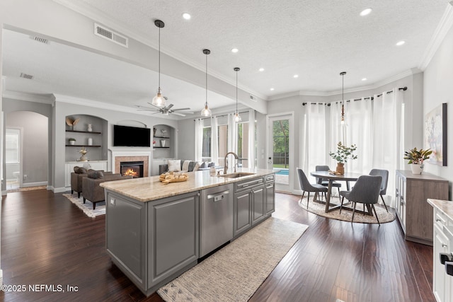 1612 Inkberry Ln, Saint Johns, FL 32259 - kitchen featuring stainless steel dishwasher, a ceiling fan, gray cabinetry, a glass covered fireplace, and a kitchen island with sink