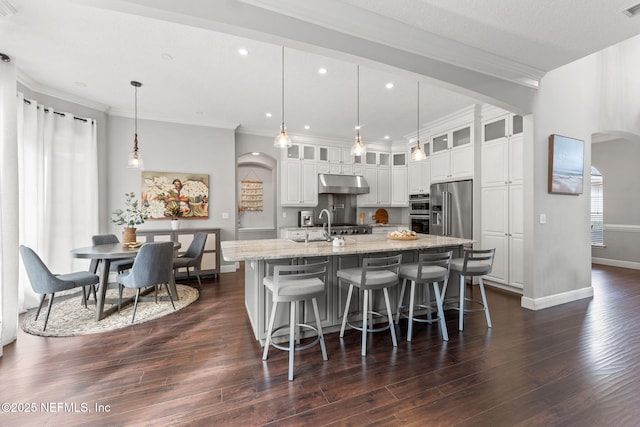 1612 Inkberry Ln, Saint Johns, FL 32259 - kitchen with under cabinet range hood, high quality fridge, arched walkways, a kitchen island with sink, and dark wood-type flooring