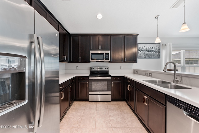 11521 Dunforth Cove Dr, Jacksonville, FL 32218 - kitchen featuring stainless steel appliances, a sink, light countertops, light tile patterned floors, and hanging light fixtures