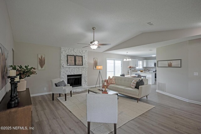 1798 Shannon Lake Dr, Middleburg, FL 32068 - living area with light wood finished floors, a ceiling fan, lofted ceiling, a stone fireplace, and baseboards