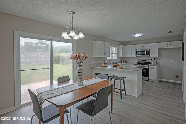 1798 Shannon Lake Dr, Middleburg, FL 32068 - dining area featuring a chandelier, a textured ceiling, light wood finished floors, and baseboards