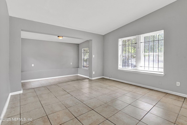 9118 Devonshire Blvd, Jacksonville, FL 32208 - empty room featuring light tile patterned floors, lofted ceiling, and baseboards