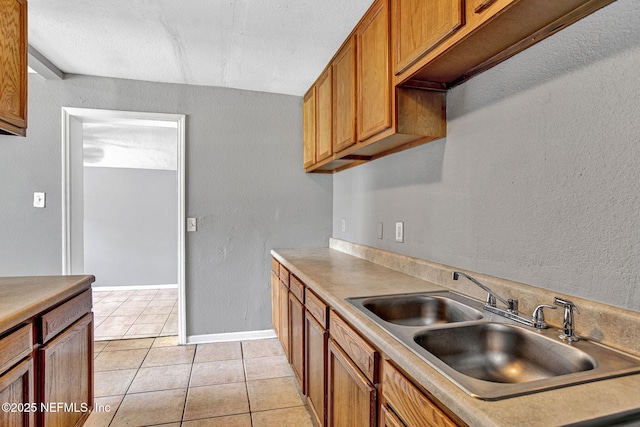 9118 Devonshire Blvd, Jacksonville, FL 32208 - kitchen with a sink, light tile patterned floors, brown cabinetry, baseboards, and light countertops