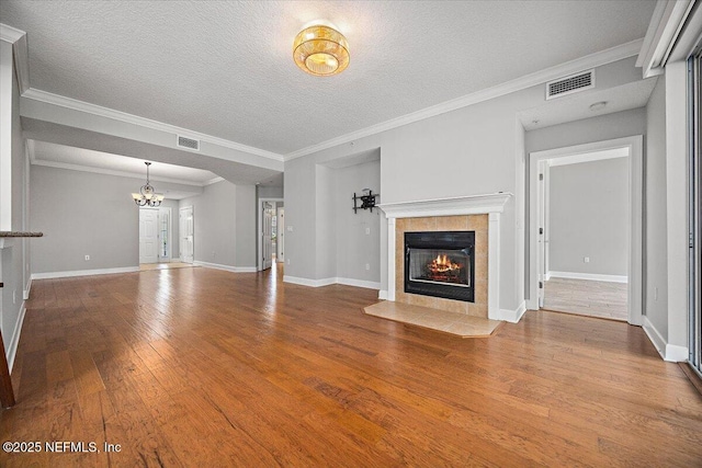 215 S Ocean Grande Dr Unit 105, Ponte Vedra Beach, FL 32082 - unfurnished living room featuring a tile fireplace, hardwood / wood-style flooring, a chandelier, a textured ceiling, and baseboards