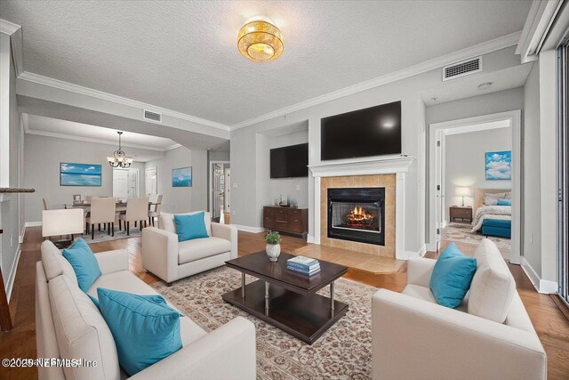 215 S Ocean Grande Dr Unit 105, Ponte Vedra Beach, FL 32082 - living room with wood finished floors, a chandelier, a tiled fireplace, baseboards, and a textured ceiling