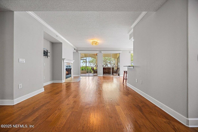 215 S Ocean Grande Dr Unit 105, Ponte Vedra Beach, FL 32082 - unfurnished living room with a fireplace with flush hearth, hardwood / wood-style floors, a textured ceiling, baseboards, and crown molding