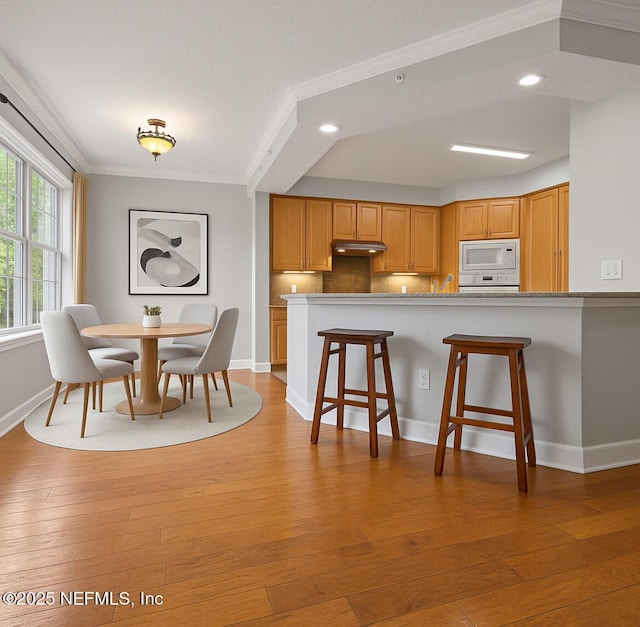 215 S Ocean Grande Dr Unit 105, Ponte Vedra Beach, FL 32082 - kitchen featuring white appliances, crown molding, a kitchen breakfast bar, light wood-type flooring, and baseboards