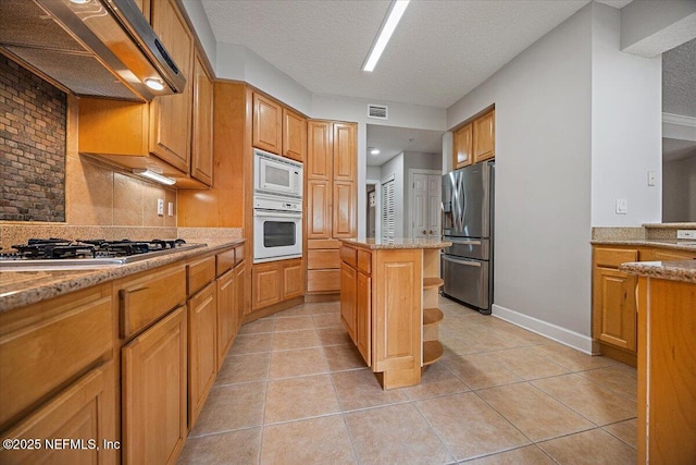 215 S Ocean Grande Dr Unit 105, Ponte Vedra Beach, FL 32082 - kitchen with appliances with stainless steel finishes, premium range hood, backsplash, light stone counters, and light tile patterned floors