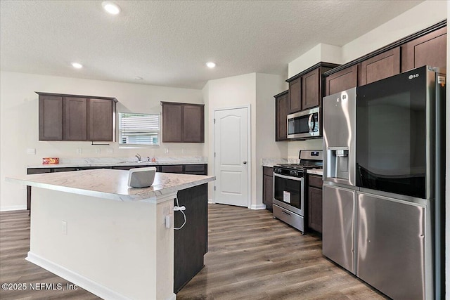 187 Logrono Ct, Saint Augustine, FL 32084 - kitchen with appliances with stainless steel finishes, dark brown cabinetry, dark wood-style flooring, a center island, and a textured ceiling