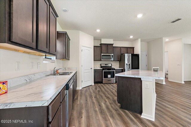 187 Logrono Ct, Saint Augustine, FL 32084 - kitchen featuring stainless steel appliances, dark wood finished floors, dark brown cabinets, a kitchen island, and baseboards