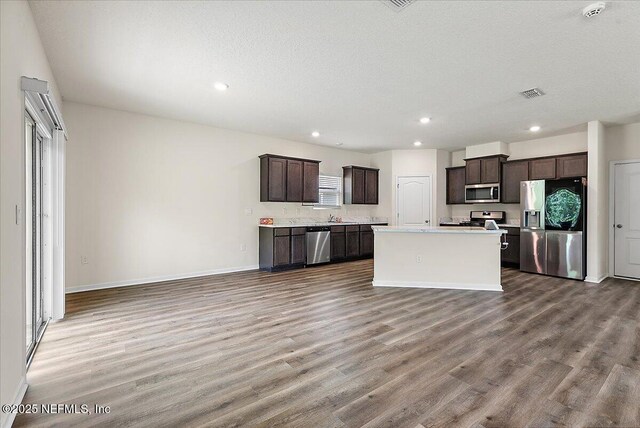 187 Logrono Ct, Saint Augustine, FL 32084 - kitchen with appliances with stainless steel finishes, dark brown cabinets, open floor plan, wood finished floors, and recessed lighting