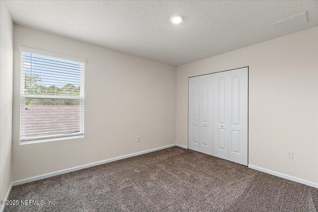187 Logrono Ct, Saint Augustine, FL 32084 - unfurnished bedroom with carpet flooring, baseboards, a closet, and a textured ceiling