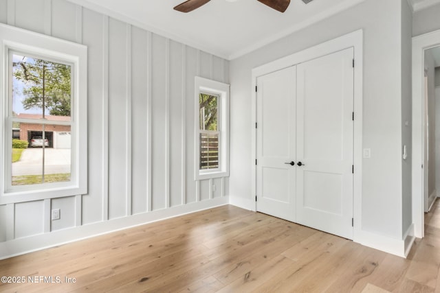 22 N 17th St, Amelia Island, FL 32034 - unfurnished bedroom featuring multiple windows, light wood finished floors, a closet, a ceiling fan, and crown molding