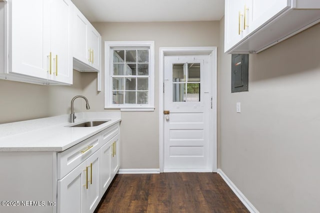 937 Stark St, Jacksonville, FL 32208 - kitchen with a sink, electric panel, dark wood-style floors, white cabinets, and baseboards