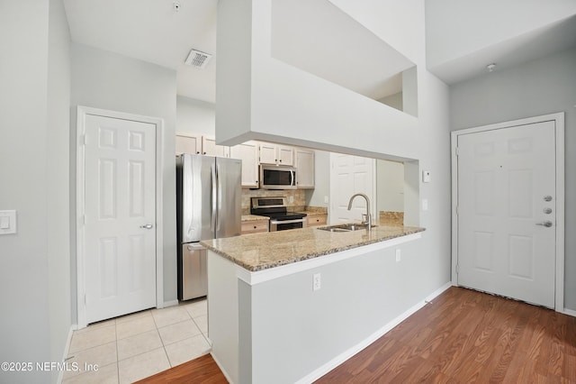 140 Veracruz Dr Unit 635, Ponte Vedra Beach, FL 32082 - kitchen with appliances with stainless steel finishes, a sink, a peninsula, a towering ceiling, and tasteful backsplash