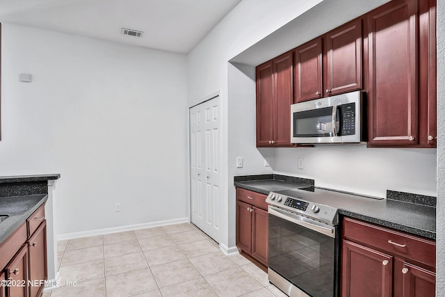 13793 Herons Landing Way Unit 4, Jacksonville, FL 32224 - kitchen with appliances with stainless steel finishes, reddish brown cabinets, dark countertops, light tile patterned floors, and baseboards
