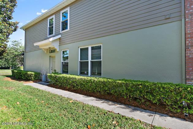 7542 Red Crane Ln, Jacksonville, FL 32256 - view of side of property featuring stucco siding and a yard