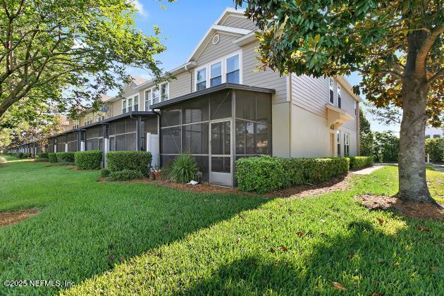 7542 Red Crane Ln, Jacksonville, FL 32256 - back of property featuring a yard, a sunroom, and stucco siding