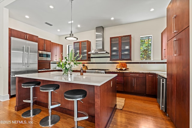 295 Sophia Ter, Saint Augustine, FL 32095 - kitchen featuring built in appliances, wall chimney range hood, wood finished floors, decorative backsplash, and glass insert cabinets