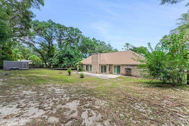 2270 Wilmhurst Rd, Deland, FL 32720 - back of house with a patio area, a chimney, brick siding, and a lawn