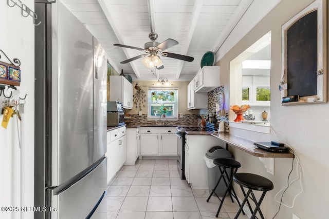 1810 Griflet Rd, Jacksonville, FL 32211 - kitchen with freestanding refrigerator, a sink, light marble finish floors, white cabinetry, and dark countertops