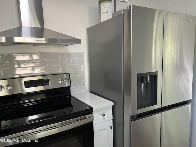 5256 Alpha Ave, Jacksonville, FL 32205 - kitchen featuring appliances with stainless steel finishes, wall chimney range hood, tasteful backsplash, white cabinets, and light countertops