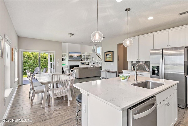 436 Marsh Cove Dr, Ponte Vedra Beach, FL 32082 - kitchen featuring appliances with stainless steel finishes, light wood-style floors, a center island with sink, white cabinets, and recessed lighting