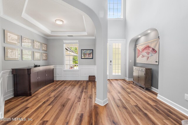 143 Istoria Dr, Saint Augustine, FL 32095 - bar featuring arched walkways, wood finished floors, a tray ceiling, crown molding, and wainscoting