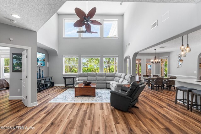 143 Istoria Dr, Saint Augustine, FL 32095 - living room featuring arched walkways, wood finished floors, a chandelier, a towering ceiling, and ceiling fan