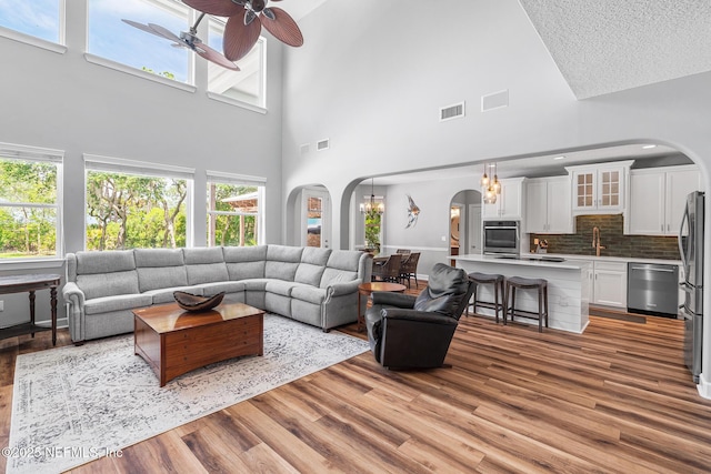 143 Istoria Dr, Saint Augustine, FL 32095 - living area with arched walkways, a towering ceiling, light wood finished floors, ceiling fan, and a textured ceiling