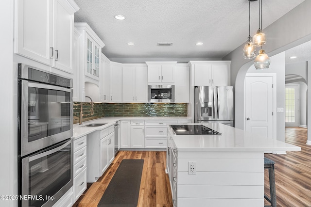 143 Istoria Dr, Saint Augustine, FL 32095 - kitchen featuring appliances with stainless steel finishes, a sink, arched walkways, a center island, and white cabinets