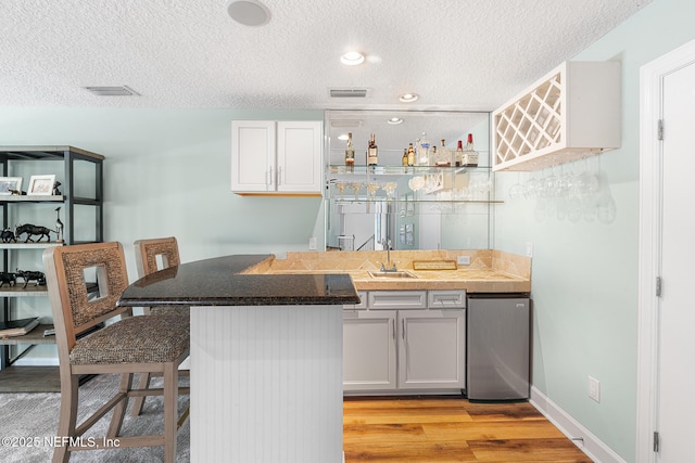 143 Istoria Dr, Saint Augustine, FL 32095 - indoor wet bar featuring a textured ceiling, light wood-style floors, stainless steel fridge, and baseboards
