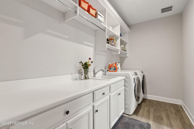 94001 Goodwood Dr, Fernandina Beach, FL 32034 - laundry area featuring washer and dryer, wood finished floors, baseboards, and cabinet space