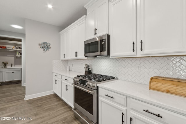 94001 Goodwood Dr, Fernandina Beach, FL 32034 - kitchen featuring stainless steel appliances, white cabinetry, tasteful backsplash, and light wood finished floors
