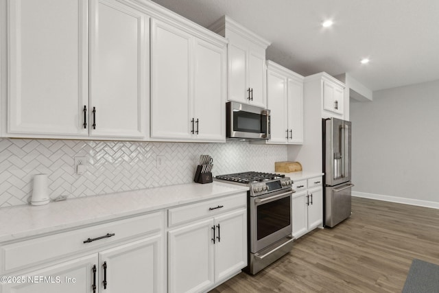 94001 Goodwood Dr, Fernandina Beach, FL 32034 - kitchen featuring stainless steel appliances, white cabinets, backsplash, recessed lighting, and light wood-style flooring