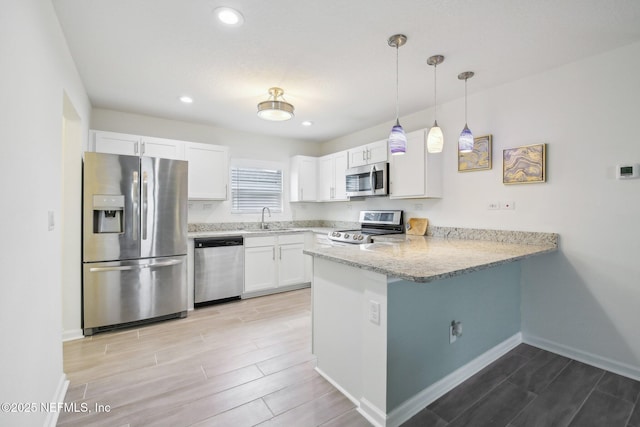 451 Sawmill Landing Dr, Saint Augustine, FL 32086 - kitchen featuring appliances with stainless steel finishes, wood tiled floors, a peninsula, white cabinetry, and baseboards